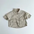 Detailansicht des khakifarbenen Baumwollhemdes mit aufgesetzten Taschen und Knöpfen - Hellbeige / 80cm
