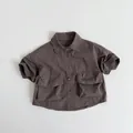 Detaillierte Flachbildaufnahme eines Kinder-Kurzarm-Baumwollhemds mit großen Taschen - Braun / 80cm