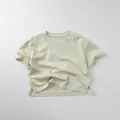 Detail view of cotton t-shirt with side split hem and minimalist knit texture - 80cm / Bean Green
