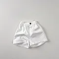 Close-up of white cotton shorts featuring elastic waist with button detail and side pockets - 80 / White