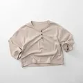 Detailed view of kids cotton long sleeve henley shirt with wood buttons and waffle texture - 80cm / Warm Apricot