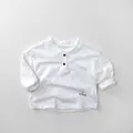 Dettaglio maglietta bianca in cotone per bambini con collo henley e ricamo leggero - 80cm / Bianco