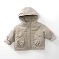 Détail d'une veste d'hiver à capuche pour enfant avec boutons et grandes poches - Abricot gris / 80cm