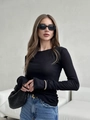 Detail eines schmal geschnittenen schwarzen Langarmshirts mit feiner Rippstrick-Textur - S / Schwarz