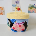 Close-up of woven cotton storage basket featuring a happy cartoon character embroidery - Pale Yellow Lid Happy Dog Style