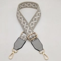 Close-up of adjustable wide woven bag strap with grey geometric pattern and gold hardware - Beige/Light Gray Pattern With Light Gray Leather