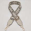 Close-up of woven ethnic bag strap with floral pattern and gold metal hardware - Beige Base Black White + Beige Leather