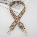 Detailed close-up of embroidered ethnic strap with gold metal buckle and lobster clasp - Beige Base Brown