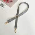 Detail view of gray adjustable nylon bag strap with gold hardware and herringbone pattern - Gray