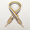 Detail van verstelbare gestreepte tasriem met gouden musketonhaken en PU-leren uiteinden - Geel & Wit Gestreepte + Khaki Leer