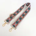 Close-up of ethnic geometric pattern woven strap with gold metal hooks and buckle - US 6