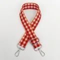 Vue détaillée d'une bandoulière tissée ajustable à carreaux orange et rouge et boucles argent - Orange + Crochet Argenté