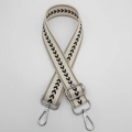 Detail view of adjustable beige nylon strap with black arrow pattern and silver hardware - Cream White + Silver Hook