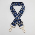 Detail of ethnic floral embroidered bag strap with golden metal hooks and adjustable slider - Black Background Blue Edge White