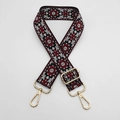 Close-up of ethnic embroidered bag strap with golden metal lobster clasps and patterns - Black Background Red Edge White