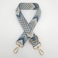 Detailaufnahme des breiten Taschenriemens mit Chevron-Muster und Goldkarabinern - Dunstblau + Goldener Haken