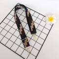 Dettaglio di un'ampia tracolla in jacquard geometrico con fibbie in metallo oro - Gancio oro chiaro / Nero