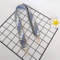 Close-up of adjustable canvas bag strap with geometric patterns and gold metal buckles - Gray