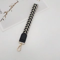 Close-up of leaf embroidery strap with black leather detail and golden lobster clasp - Black With Gasket