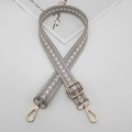 Detail view of grey nylon bag strap with white arrow pattern and golden metal buckles - Beige Grey