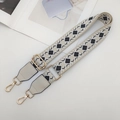 Close-up of geometric patterned wide crossbody bag strap with gold metal buckles - Beige/Black with Cream Leather