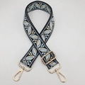 Detailed view of woven guitar style bag strap with floral pattern and gold metal hardware - Black Base Light Blue