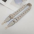 Close-up of geometric jacquard woven strap with golden lobster clasps and grey leather ends - Beige/White/Khaki with Cream Leather
