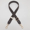 Detail of adjustable cotton webbing bag strap with gold metal hardware and faux leather ends - Brown
