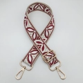 Close-up of ethnic woven floral guitar style bag strap with gold metal lobster clasps - Beige Base Wine Red
