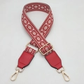 Close-up of red ethnic jacquard bag strap with geometric diamond patterns and gold hooks - Red + Red Leather
