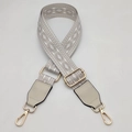 Detail view of adjustable jacquard woven bag strap with golden metal lobster clasps - Beige Gray White With Cream Leather