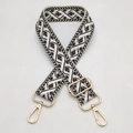 Detail view of woven geometric bag strap with polished gold-tone lobster clasps and buckles - Beige Base Black White