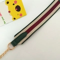 Détail de la bandoulière rayée rouge et blanc avec cuir vert et chaîne dorée - Rayures vertes