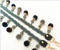 Détail d'une bandoulière tissée vert foncé avec pompons colorés et fermoirs dorés - Style Pompon 120