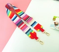 Detail van verstelbare regenboog gestreepte tasriem met gouden gespen en rood lederen eind - 01 Helder Rood