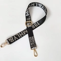 Close-up of black nylon bag strap with silver lettering and golden metal hook hardware - White Letters (Gold Buckle)