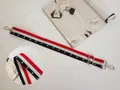 Detail eines breiten Stoff-Taschenriemens mit rot-weiß-blauen Streifen und Sternen - Sternenmuster (Goldschnalle)