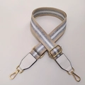 Detalle de correa ajustable beige con rayas plateadas brillantes y ganchos de metal dorado - Ancho: 3.8cm / Correa Caqui con Extremo Blanco