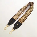 Detail eines verstellbaren gewebten Schultergurts mit gelben Mustern und Goldclips - Khaki & Schwarz
