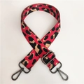Detail of red leopard print nylon strap with dark grey metal hooks and buckle - Red Gunmetal Buckle