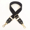 Detail of black canvas shoulder strap with golden metal hardware and leather ends - Black