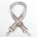 Detail von Taschenriemen aus khakifarbenem Nylon mit weißem V-Muster und Goldkarabinern - Hellbeige Goldene Schnalle