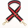 Detail view of wide black nylon bag strap with red stripe and golden metal lobster clasps - Black/Red/Black