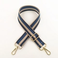 Detail van de verstelbare blauw en beige gestreepte tasriem met gouden metalen karabijnsloten - Blauw