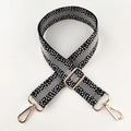 Detail eines verstellbaren breiten Taschenriemens mit schwarz-weißem Muster und Goldhaken - Schwarz Grau Goldene Schnalle