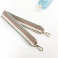 Detail view of woven striped bag strap with golden lobster clasps on white surface - Bean Green Short Style