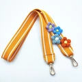 Detail of orange woven bag strap featuring colorful crochet flowers and gold lobster clasps - Yellow Long Style