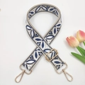 Close-up of embroidered bag strap with blue leaf patterns and golden metal hardware - Beige Navy Blue