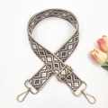 Detail of adjustable geometric weave bag strap with gold metal buckles and swivel hooks - Beige base Light Coffee