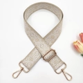 Macro view of adjustable 3.8cm woven shoulder strap with gold metal buckles and pattern - Beige base White